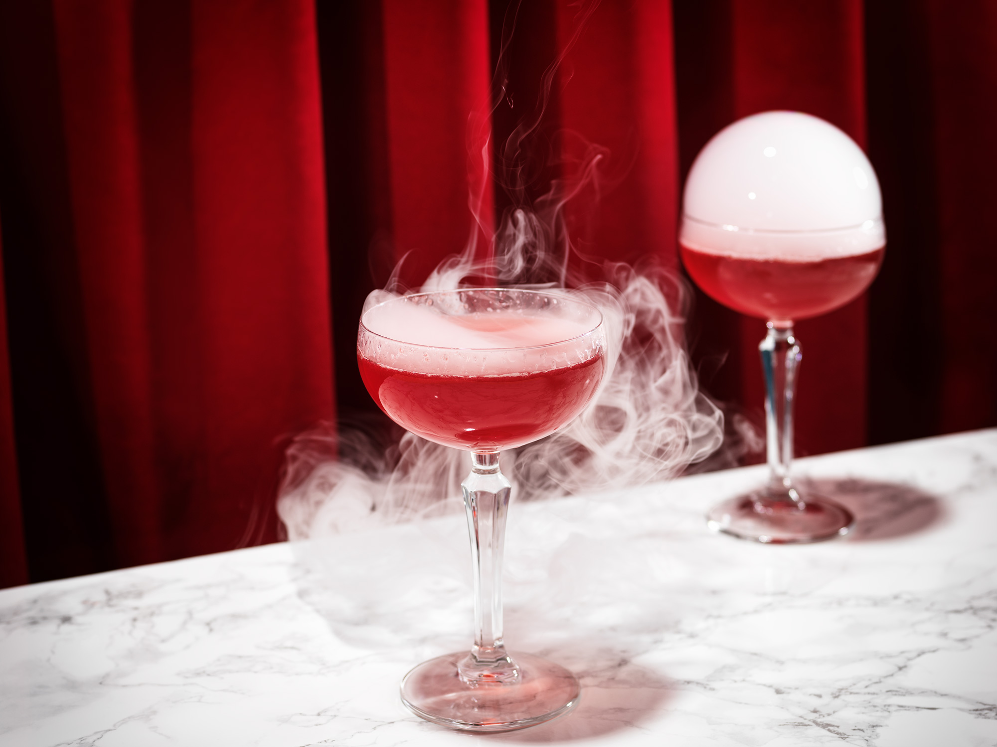 bildstadt Foodfotografie – Kenny Klein Cocktails - roter Cocktail mit geplatzter Rauchblase und rotem Vorhang in Hintergrund